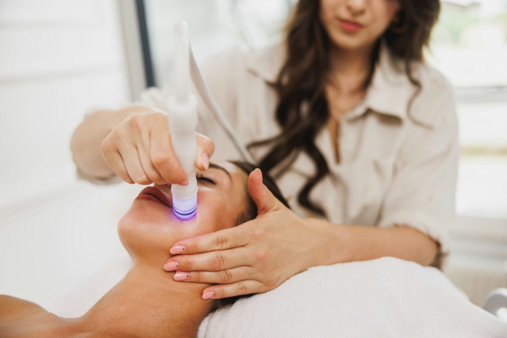 Beauty Therapist Performing Hydrafacial Procedure On Woman